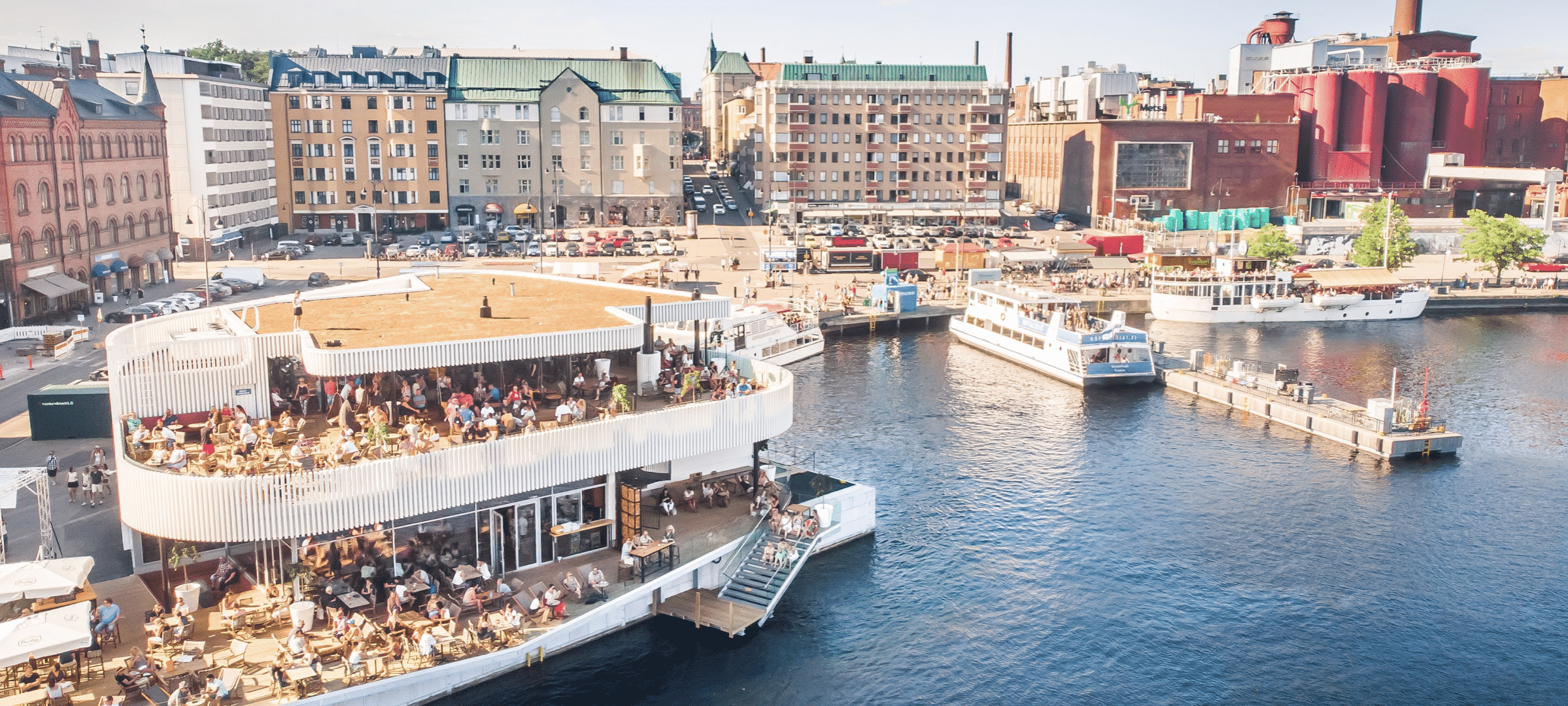 Sauna restaurant Kuuma with its terrace in the foreground, Laukontori harbour of Tampere in the background.