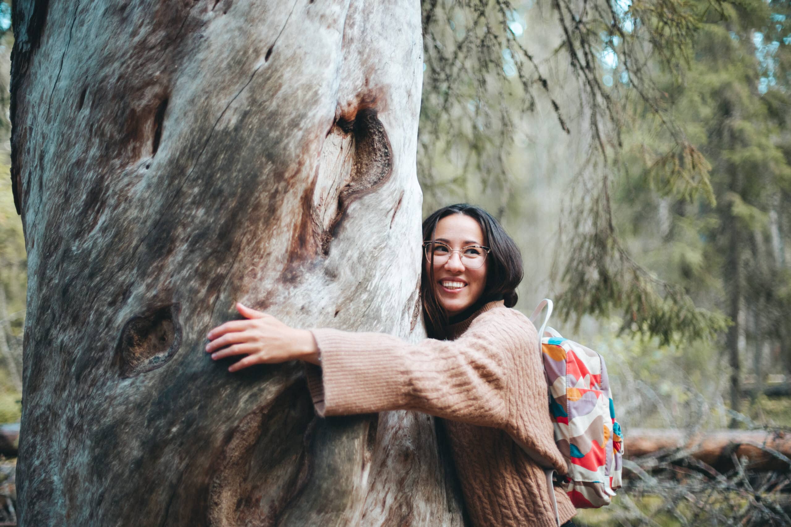 Person smiling and hugging a tree