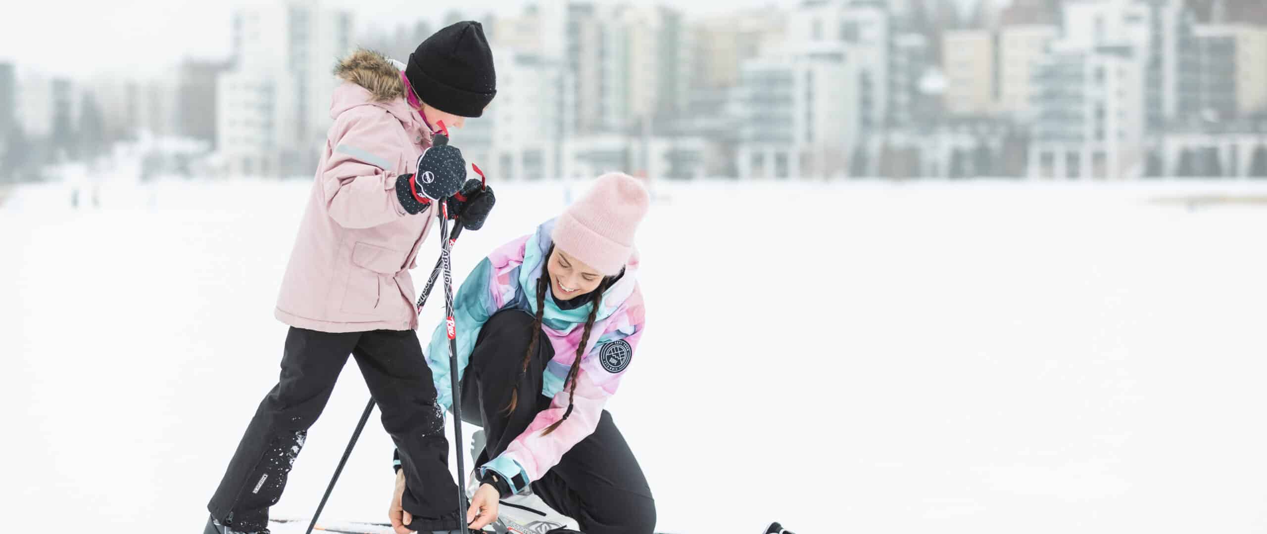 Adult helping a child with their trousers on a frozen lake.