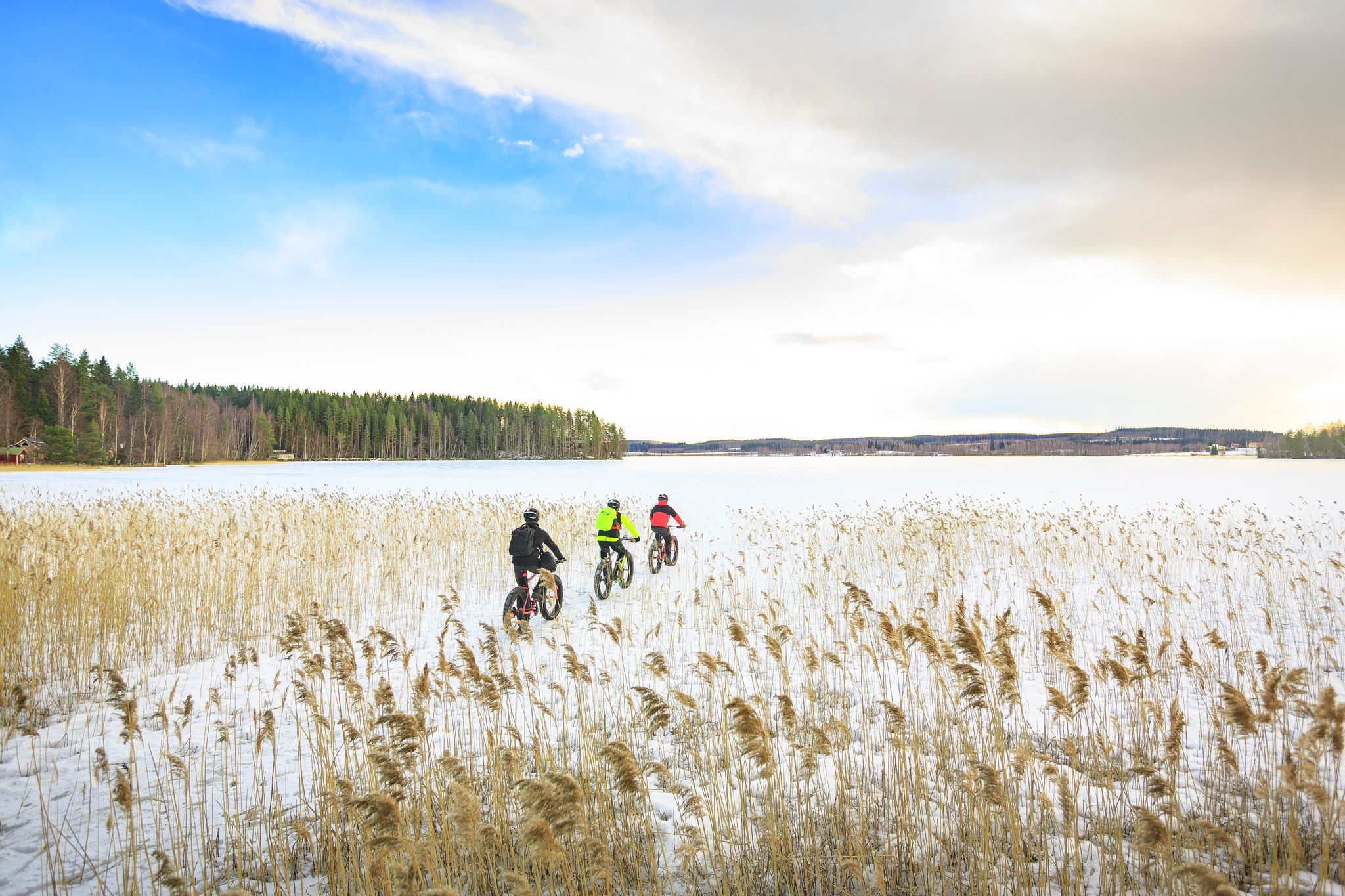 Three persons cycling on a frozen lake.