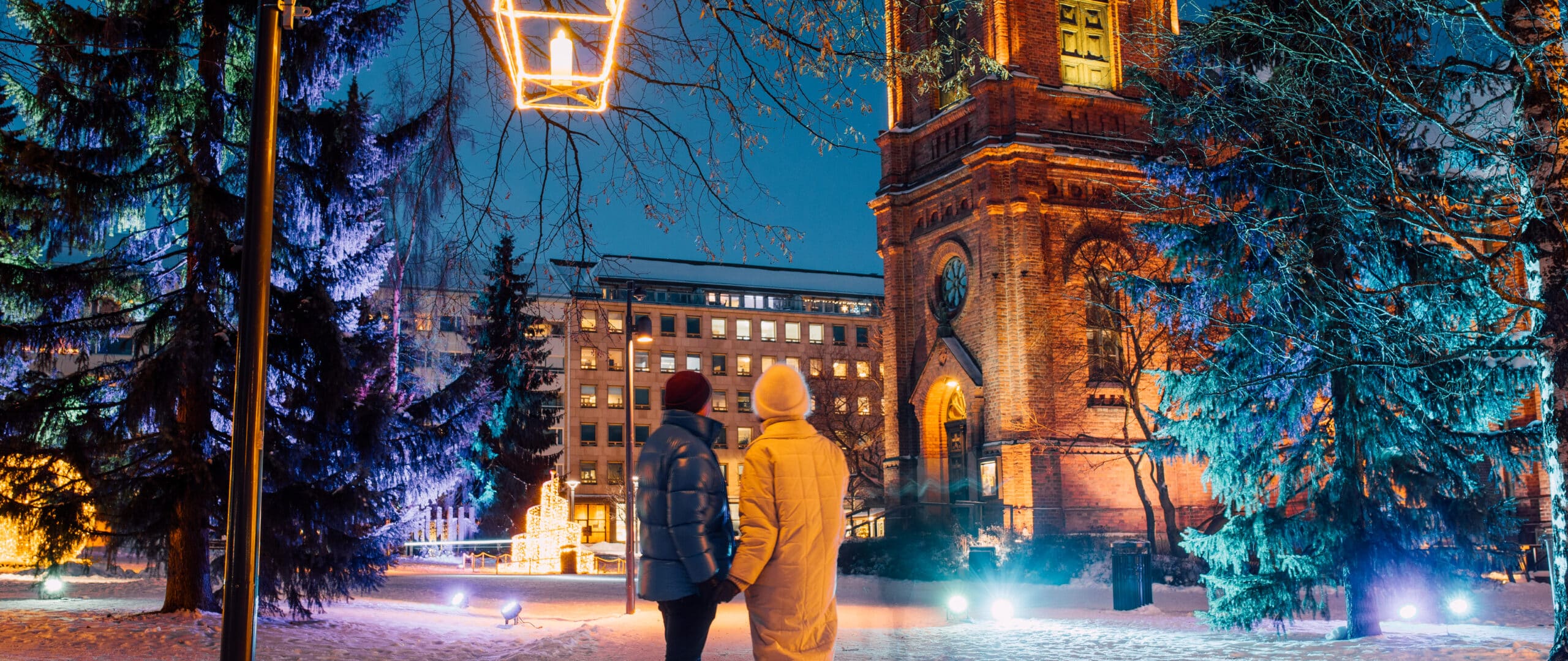 Two persons standing in Jyväskylä's snowy Church Park.