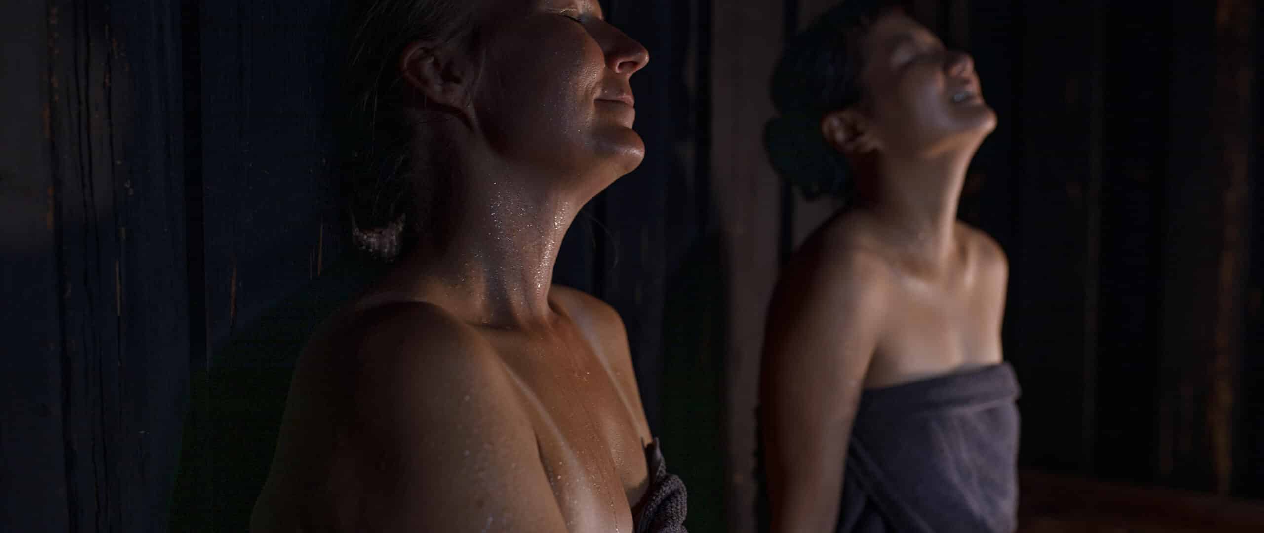 Two persons relaxing eyes closed in a sauna.